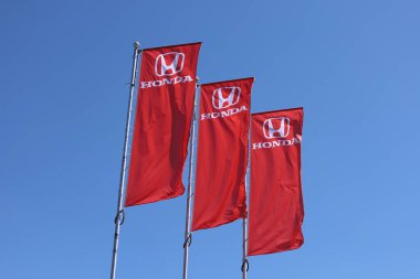Poznan, Polonya - 14 Mayıs 2024. Mavi arka planda sallanan bayraklar üzerinde Honda logosu.