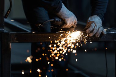 Öğütücüyle demir üzerinde çalışan adam. İş yerinde bir adam. Öğütücüden çıkan kıvılcımlar ve ateş. Öğütücü. İşçi.