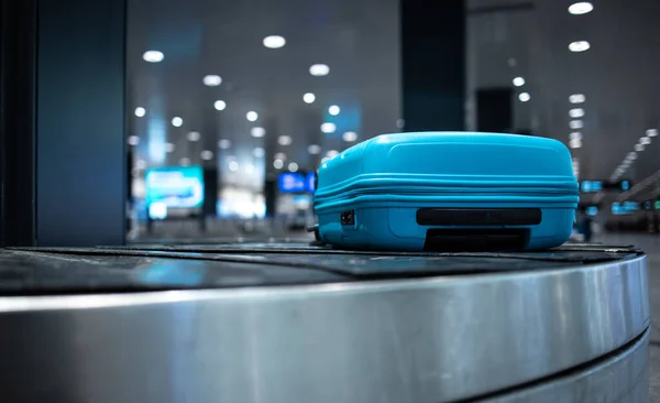 Arrived luggage going around on a conveyor belt waiting to be claimed at the baggage claim zone at a modern international airport