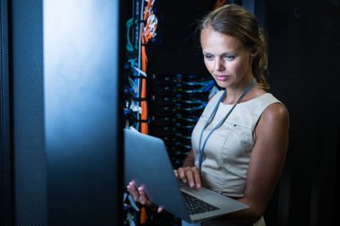 BT mühendisi sunucu rafında çalışırken dizüstü bilgisayar kullanarak rutin bakım ve tanı kontrolü yapıyor.