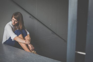 Depresyonda olan genç bir kadın merdivende oturuyor. Coronavirüs salgını yüzünden Jobloss, Covid-19 salgını. İşsizlik, ekonomik kriz, mali sıkıntı kavramı