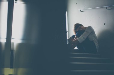 Depresyonda olan genç bir kadın merdivende oturuyor. Coronavirüs salgını yüzünden Jobloss, Covid-19 salgını. İşsizlik, ekonomik kriz, mali sıkıntı kavramı