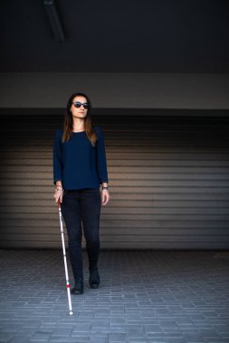 Görme engelli genç bir kadın, beyaz bastonuyla şehirde daha iyi geziniyor ve gideceği yere güvenli bir şekilde varıyor.