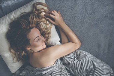 Güzel, genç bir kadın hafta sonu geç saatlere kadar yatağında uyuyor. Uykusuzluğunu telafi ediyor.