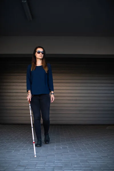 都市空間をよりよくナビゲートし 安全に彼女の目的地に到達するために彼女の白い杖を使用して 都市の通りを歩く視覚障害者の若い女性 — ストック写真