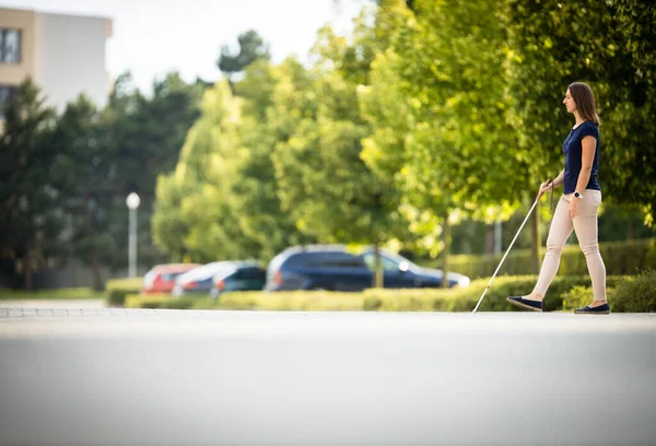 白い杖を使って街を歩く視覚障害のある若い女性 — ストック写真