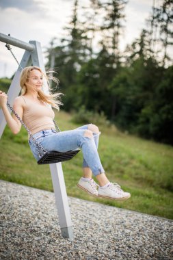 Salıncakta sallanan romantik bir bahar kadını. Web sitesi başlığı için pankart. Kaygısız kadın yazın tadını çıkarır. Genç kadın salıncakta sallanıyor yaz parkı bahçesinde.