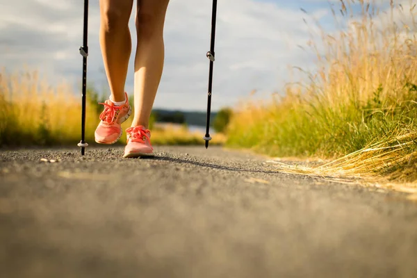 美しい夏の日に外を歩くかなり若い女性の健康な足 極のあるノルディックウォーキング ストック画像