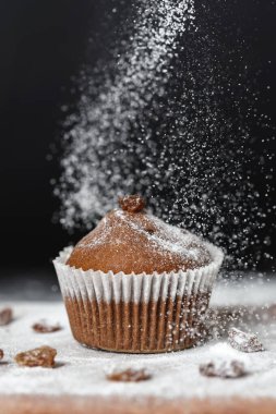 Tahtanın üzerine toz şeker serpiştirilmiş taze muffinler.
