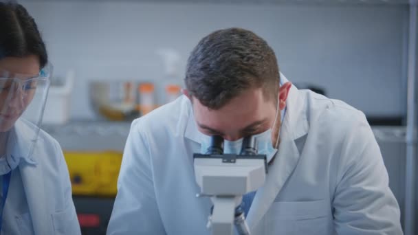 Trabalhadoras Laboratório Masculinas Femininas Que Realizam Pesquisas Usando Microscópio Anotando — Vídeo de Stock