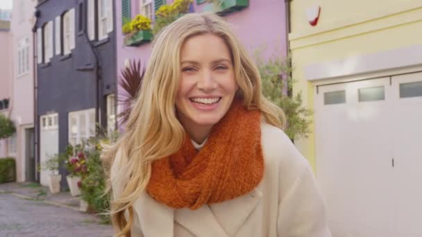 コートやスカーフを身に着けている笑顔の女性の肖像は 秋や冬に市への訪問で石畳のミューズ通りに立って スローモーションで撮影 — ストック動画
