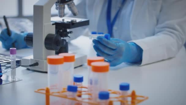 Beyaz Önlüklü Bilim Adamının Mikroskoptan Bakıp Elinde Test Tüpü Tutarken — Stok video