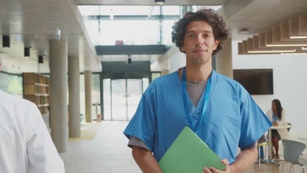 在繁忙的医院大楼里穿着洗涤剂记录病人病历的笑脸男医生的画像 慢镜头拍摄 — 图库视频影像