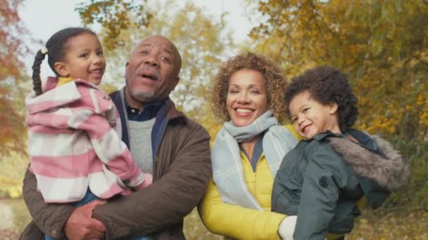 Lächelnde Großeltern Tragen Kinder Beim Spaziergang Durch Die Herbstliche Landschaft — Stockvideo