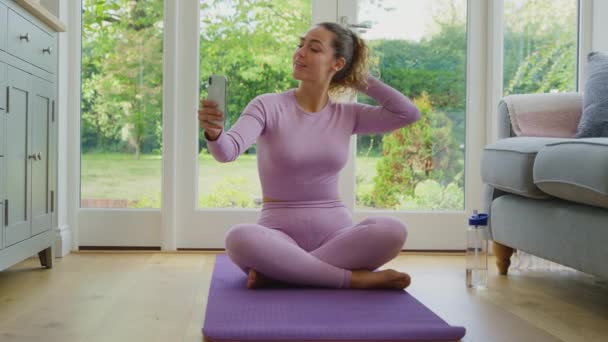 Młoda Kobieta Siedząca Macie Jogi Domu Ćwiczeniach Pozująca Selfie Telefonie — Wideo stockowe