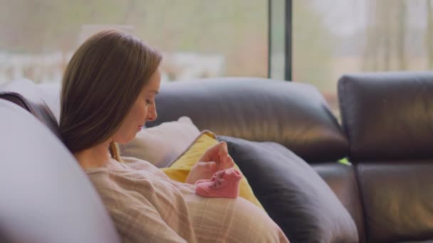 Pregnant Woman Sitting Sofa Home Looking Small Baby Shoes Shot — Stock Video