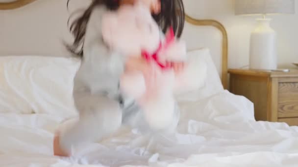 Menina Jogando Cama Usando Pijama Casa Abraçando Ursinho Pelúcia Tiro — Vídeo de Stock