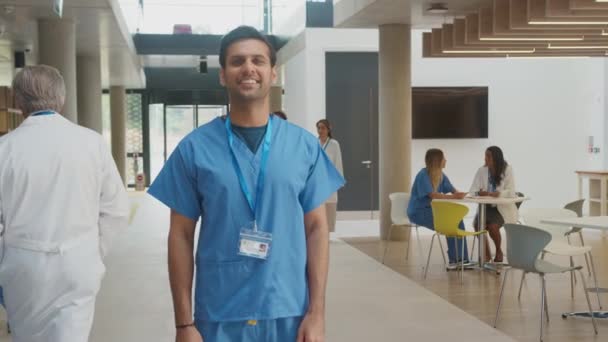 笑顔の男性医師の肖像画を身に着けているスクラブ立って 忙しい病院の建物で腕を折る スローモーションで撮影 — ストック動画