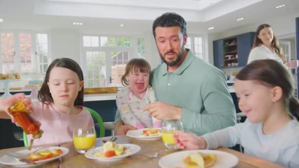 患有唐氏综合症的家庭女儿坐在桌旁 吃着煎饼 水果和糖浆当早餐 动作缓慢 — 图库视频影像