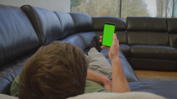 Pria Mengenakan Piyama Berbaring Sofa Rumah Melihat Layar Hijau Ponsel — Stok Video