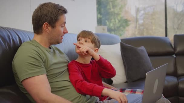 Pai Filho Sentados Sofá Casa Pijama Juntos Olhando Para Laptop — Vídeo de Stock