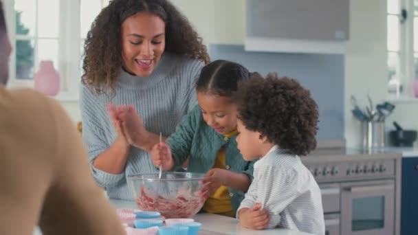 カップケーキ用のボウルに一緒に食材を混合キッチンで親と子供 スローモーションで撮影 — ストック動画