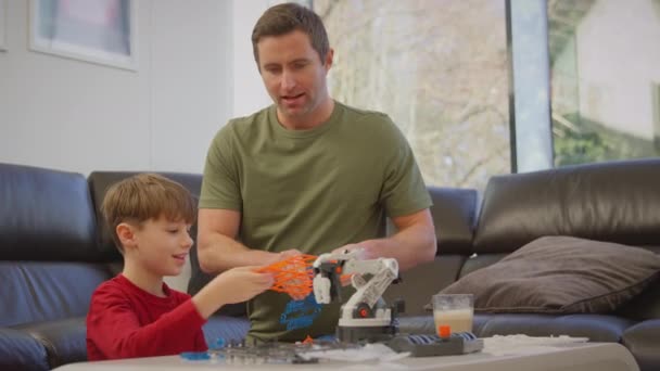 爸爸和儿子穿着睡衣 从家里的塑料套件上造出机械臂 用于科学项目 慢镜头拍摄 — 图库视频影像