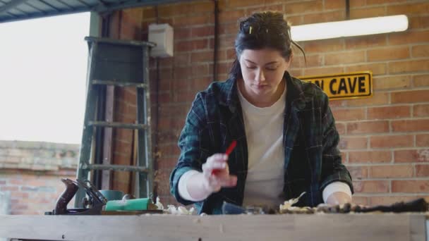 车库车间的年轻女木匠戴着眼镜 用铅笔慢镜头在纸上画出图案 — 图库视频影像