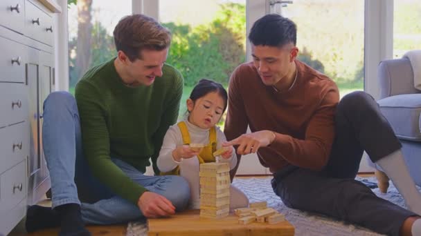 2人のお父さんと一緒にゲームをプレイしている家族とともに家に木のレンガを積み上げて塔に スローモーションで撮影 — ストック動画