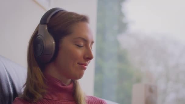 Femme Portant Casque Sans Fil Écoutant Musique Assise Sur Canapé — Video