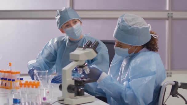 Pracownica Laboratorium Wózku Inwalidzkim Nosząca Śoi Analizujące Próbki Laboratorium Mikroskopem — Wideo stockowe