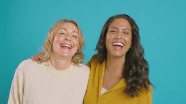 两个成熟的女性朋友在蓝色背景下对着相机笑的画像 慢镜头 — 图库视频影像