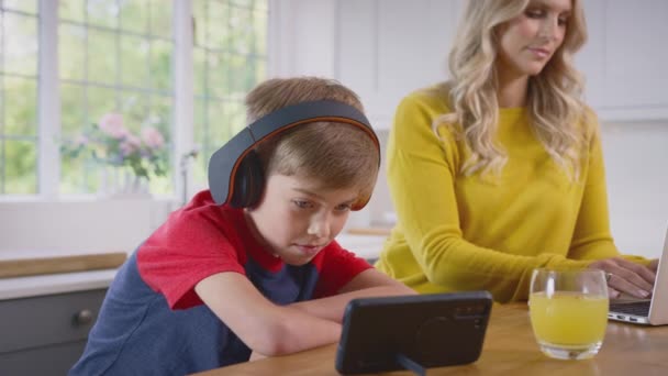 Chłopiec Noszący Słuchawki Bezprzewodowe Domu Kuchni Streaming Filmu Telefon Komórkowy — Wideo stockowe