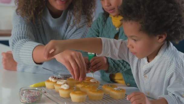 Közelkép Anya Gyerekek Konyhában Szórás Cukormáz Díszíteni Cupcakes Együtt Lelassult — Stock videók
