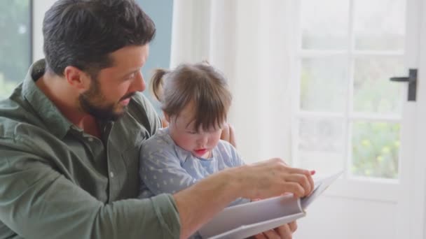 唐氏综合症女孩和父亲一起坐在家里看书 动作缓慢 — 图库视频影像