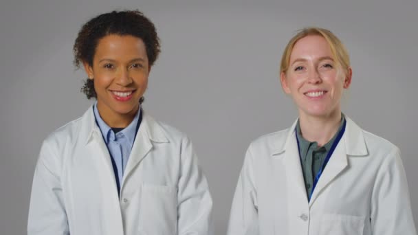 两名身穿白衣 面带微笑的女医生或实验室工作人员的工作室肖像 动作缓慢 — 图库视频影像