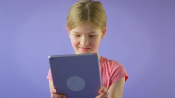 在紫色工作室背景下使用数码平板电脑拍摄微笑女孩的演播室照片 慢动作拍摄 — 图库视频影像