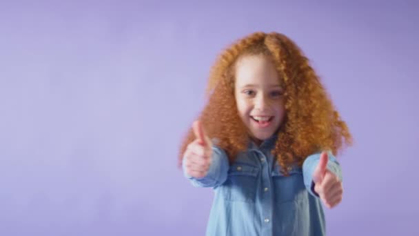 工作室拍摄的是红头发女孩在紫色背景下竖起双拇指的照片 慢动作射击 — 图库视频影像