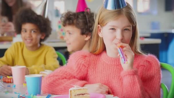 女の子の肖像画はパーティーブロワーとテーブルに座って誕生日を祝う誕生日ケーキの一部で スローモーションで撮影 — ストック動画