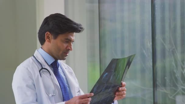 MriやCtスキャンを見て病院の廊下に立って白いコートを身に着けている男性医師 スローモーションで撮影 — ストック動画