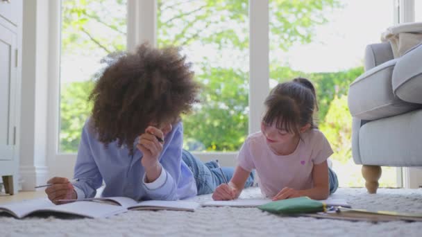 男孩和女孩在家里的休息厅里躺在地毯上一起做作业 动作缓慢 — 图库视频影像