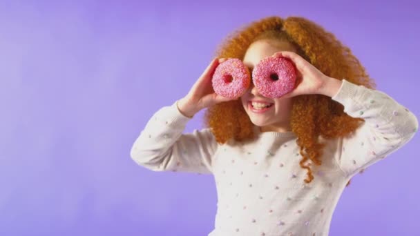 Στιγμιότυπο Στούντιο Μια Κοκκινομάλλα Νεαρή Κοπέλα Κρατάει Δύο Ντόνατς Μπροστά — Αρχείο Βίντεο