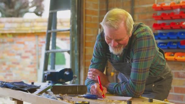 Senior Pria Mengenakan Overall Dalam Sketsa Desain Meja Kerja Bengkel — Stok Video