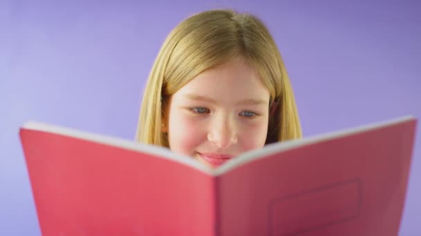 Studioショットの女の子勉強学校運動本に対して紫の背景 ショットでスローモーション — ストック動画