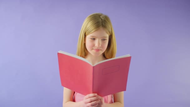 Mor Arkaplanla Kıyaslandığında Kızın Okul Egzersiz Kitabı Çalışmasının Stüdyo Fotoğrafı — Stok video
