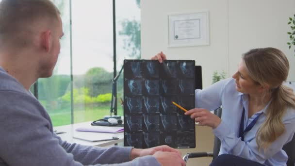 若い男性患者とCtスキャンを議論オフィスで成熟した女性医師 スローモーションで撮影 — ストック動画