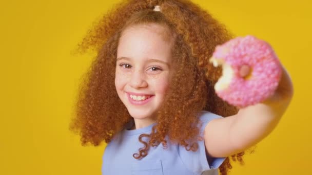 Στούντιο Πλάνο Του Κοριτσιού Κόκκινα Μαλλιά Τρώει Ντόνατ Κίτρινο Φόντο — Αρχείο Βίντεο