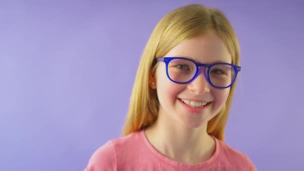 带着蓝色眼镜的长发女孩背对着紫色工作室背景的照片 慢镜头 — 图库视频影像