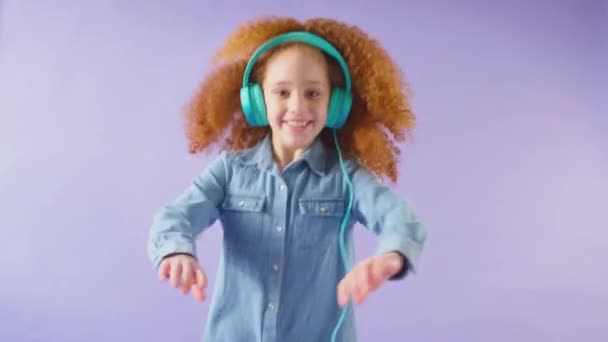 Studioaufnahme Eines Mädchens Mit Kopfhörern Das Vor Violettem Hintergrund Tanzt — Stockvideo