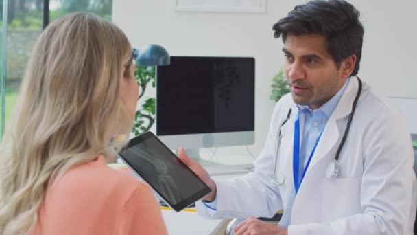 医生在办公室穿着白色外套 与成熟的女性病人一起看医学X光或慢动作地在数字桌子上扫描 — 图库视频影像